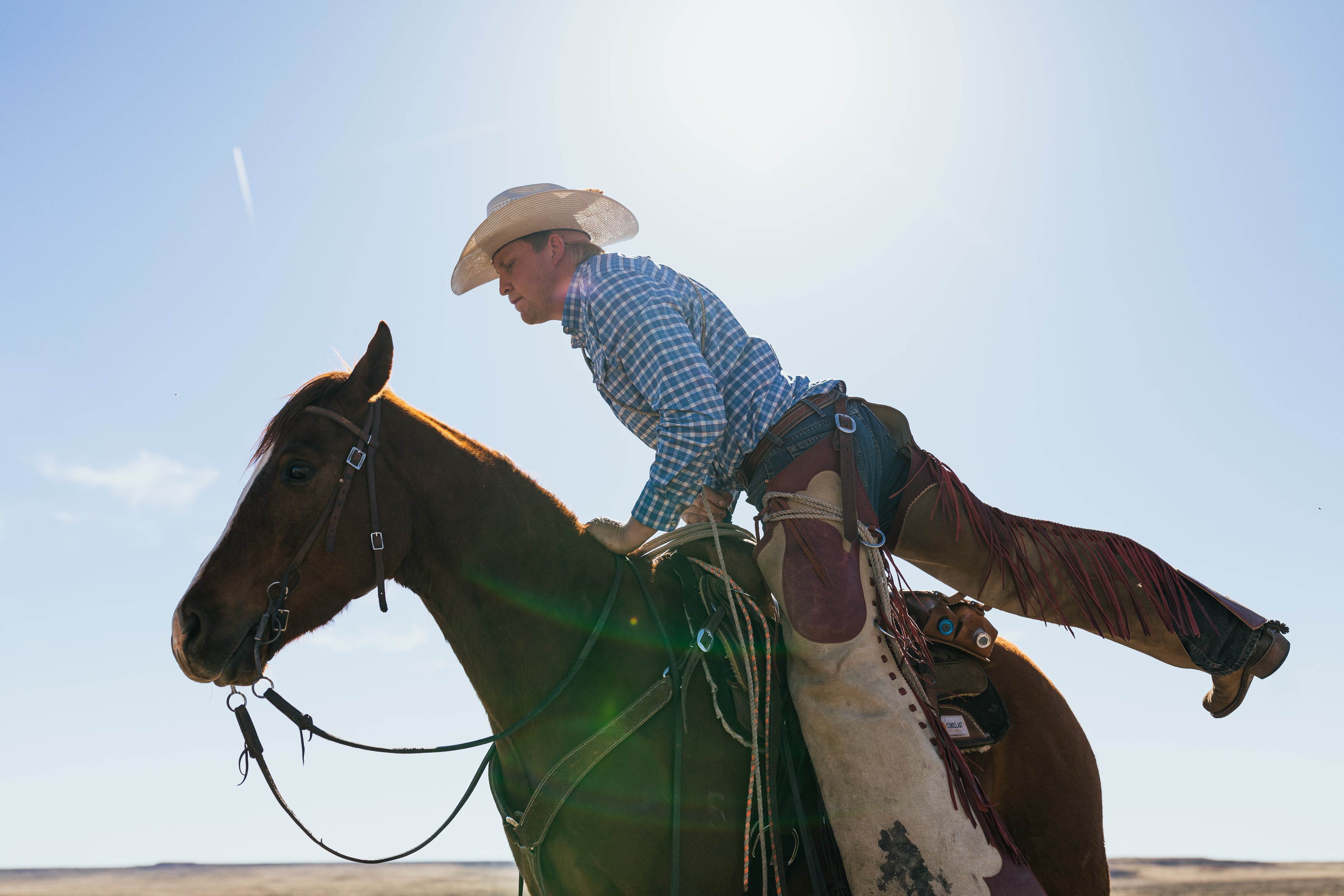 cowboy mounting horse with blue sky background