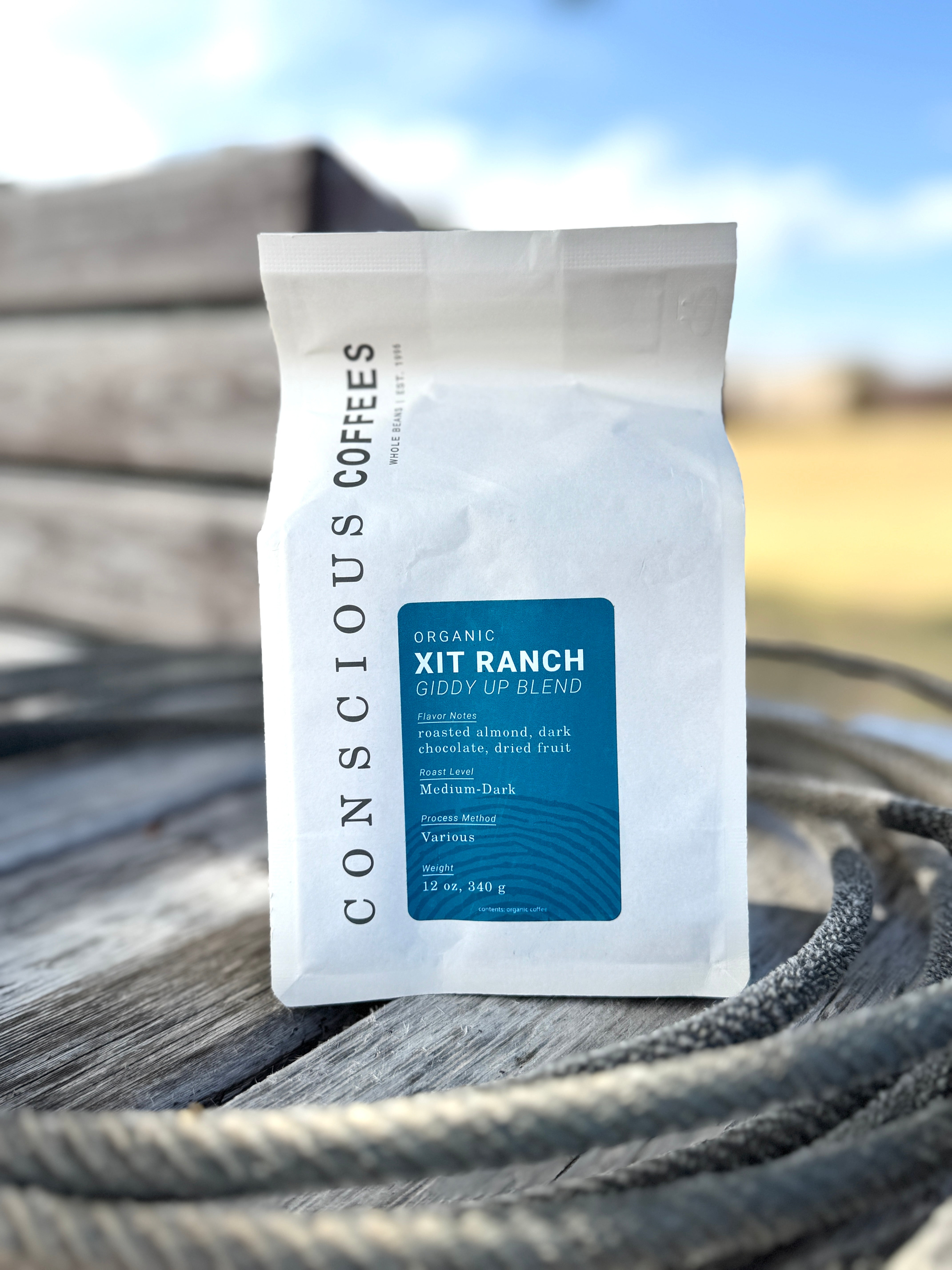 Conscious Coffees XIT Ranch Giddy Up Blend coffee package on a wooden surface with blurred background